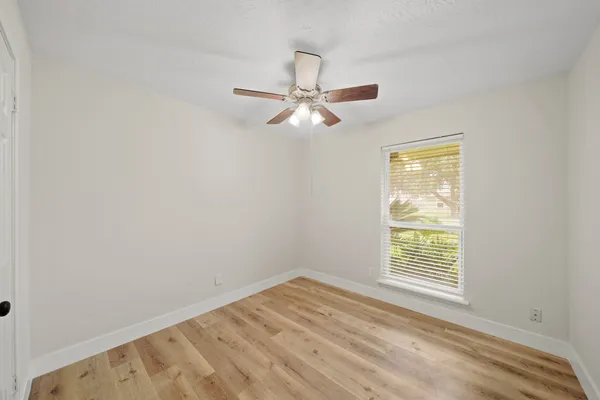 an empty room with a window and a fan