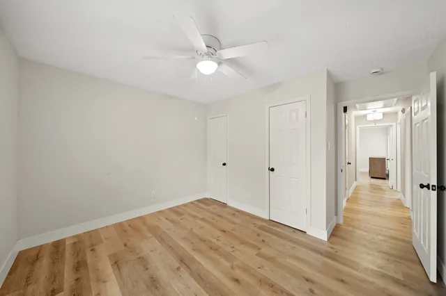 a view of a hallway with wooden floor and a ceiling fan