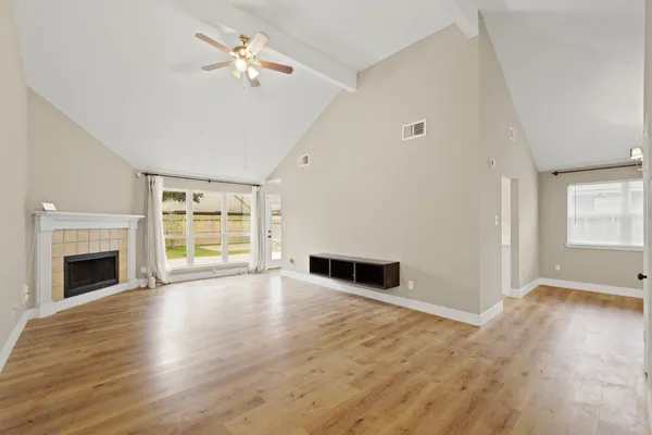 a view of empty room with wooden floor fireplace and window