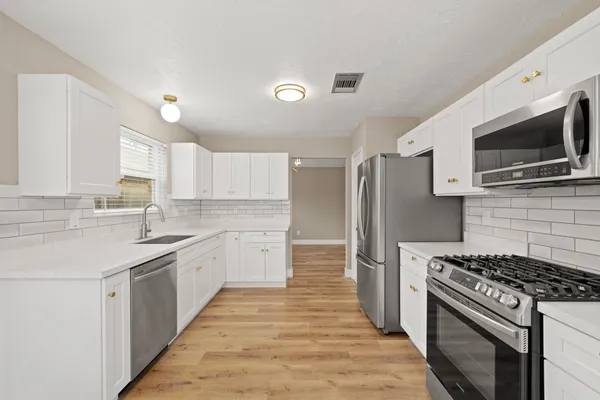 a kitchen with stainless steel appliances a sink dishwasher a refrigerator and a stove