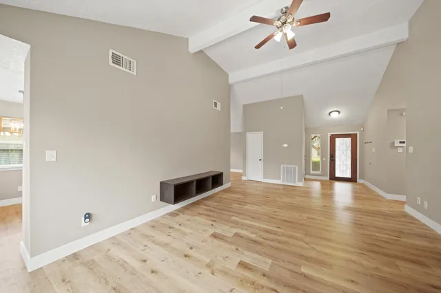 a view of empty room with wooden floor and fan