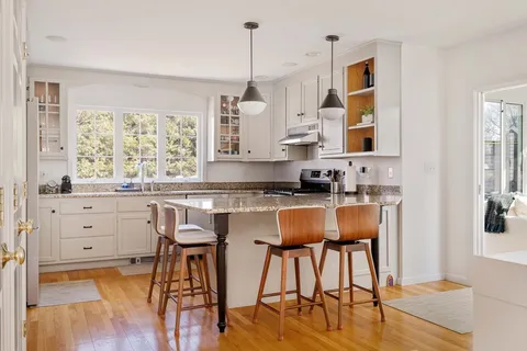 a kitchen with granite countertop a table chairs stove and white cabinets