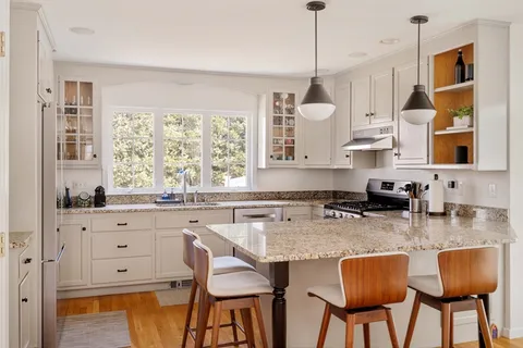 a kitchen with stainless steel appliances granite countertop a table chairs sink and cabinets