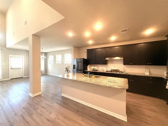 a kitchen with stainless steel appliances granite countertop a refrigerator a sink dishwasher a stove and white countertops with wooden floor