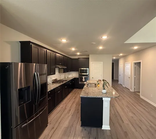 a large white kitchen with wooden floors and stainless steel appliances