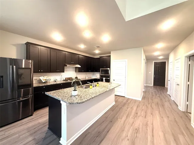 a large kitchen with a center island wooden floor stainless steel appliances and a window