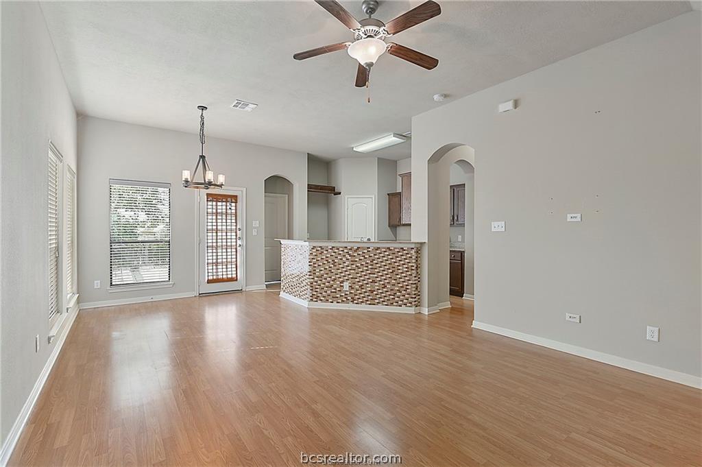 2004 Spring Leaf Court Bryan, TX 77807 - Photo 3 of 19 Unfurnished living room with ceiling fan with notable chandelier, baseboards, arched walkways, light wood finished floors, and visible vents