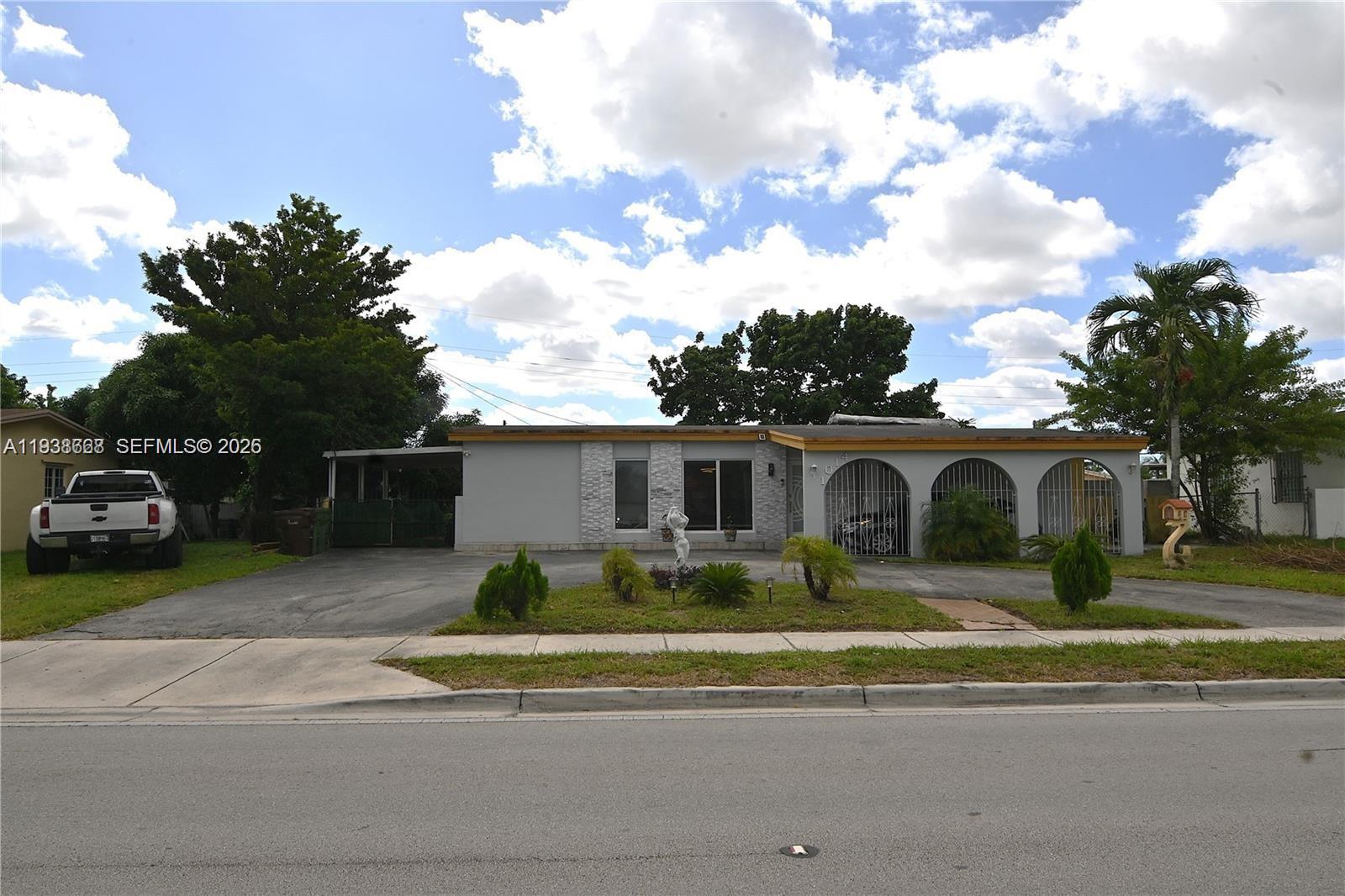1014 West 68th Street Hialeah, FL 33014 - Photo 1 of 40 a front view of a house with a garden and trees