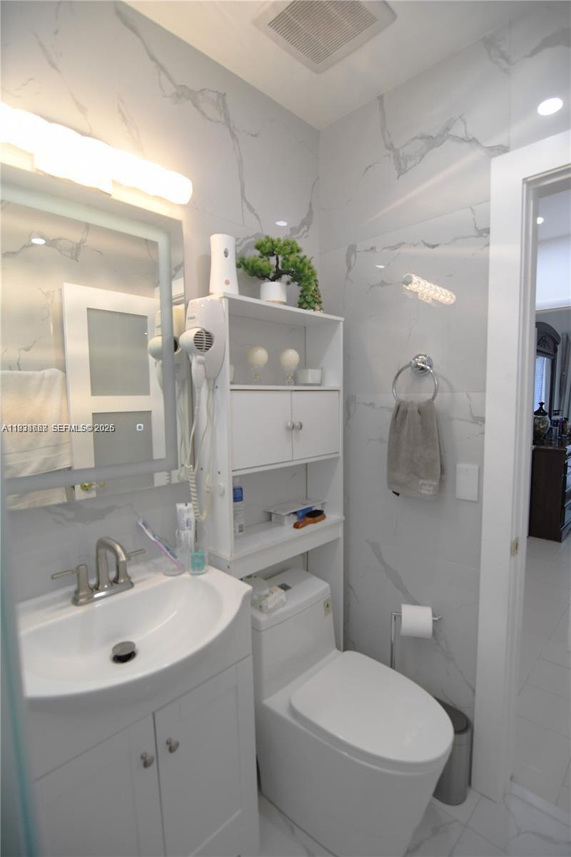 1014 West 68th Street Hialeah, FL 33014 - Photo 16 of 40 a bathroom with a toilet sink and mirror