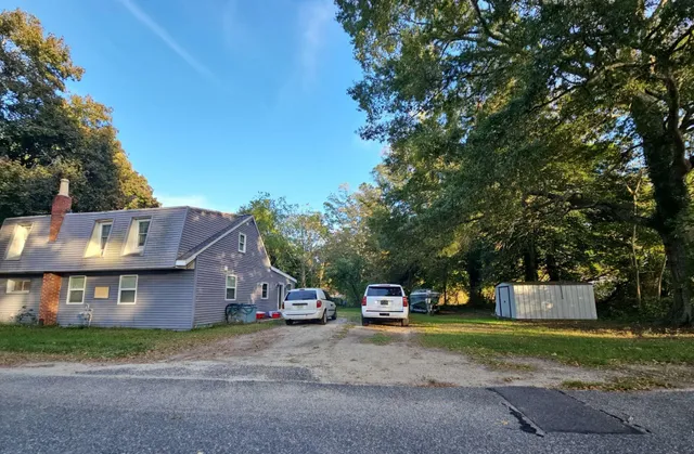 a front view of a house with a yard and a tree