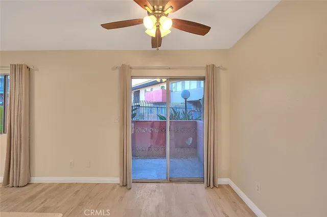 an empty room with wooden floor fan and windows