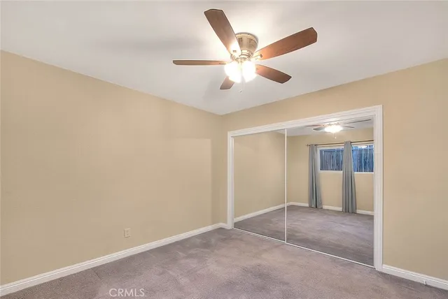 an empty room with closet and a chandelier fan