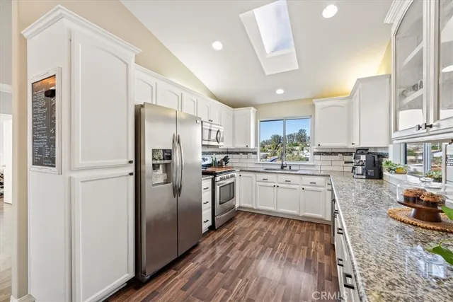 a kitchen with kitchen island granite countertop a sink cabinets and stainless steel appliances