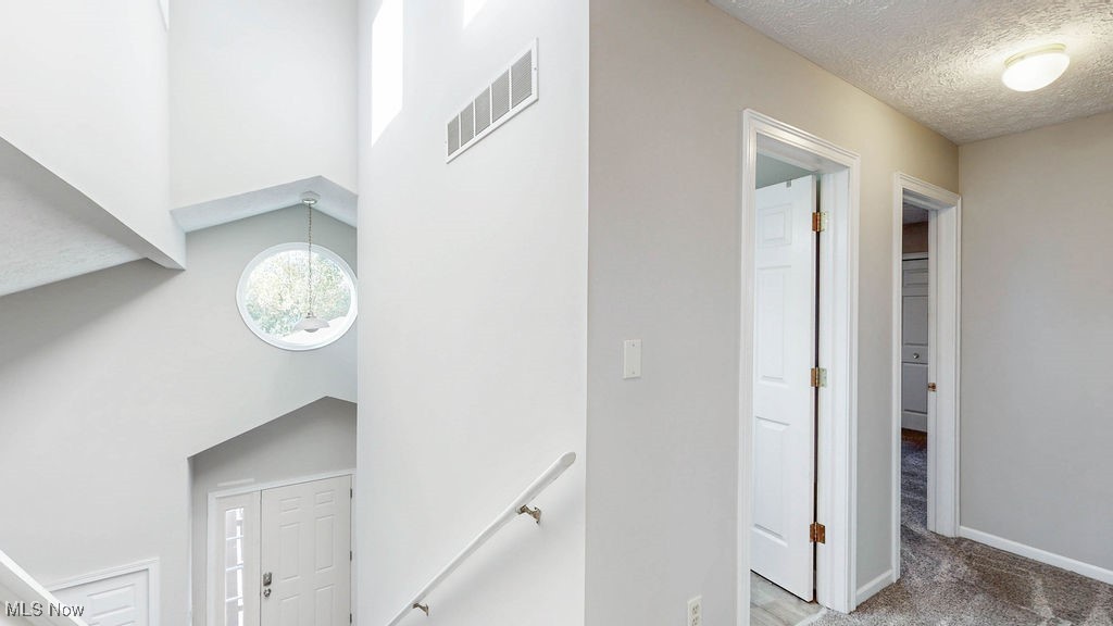1426 Loop Road, Unit 1426 Kent, OH 44240 - Photo 17 of 40 Stairway with a high ceiling, a textured ceiling, a chandelier, and carpet flooring