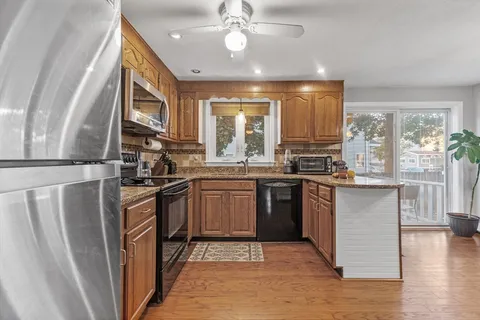 a kitchen with granite countertop a stove top oven a sink and dishwasher a refrigerator with wooden floor