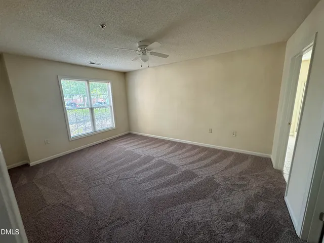 en empty room with windows and chandelier fan