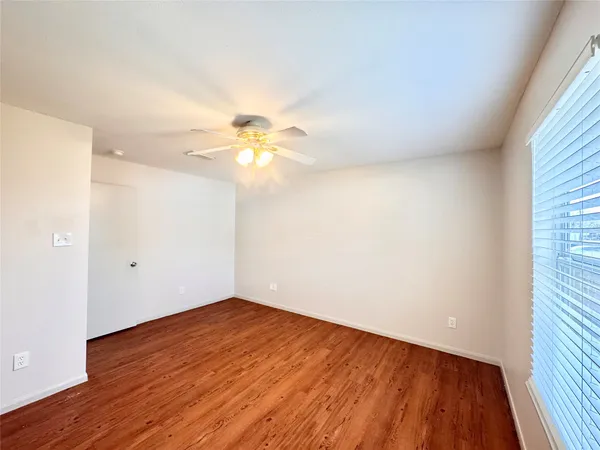 an empty room with wooden floor and chandelier fan
