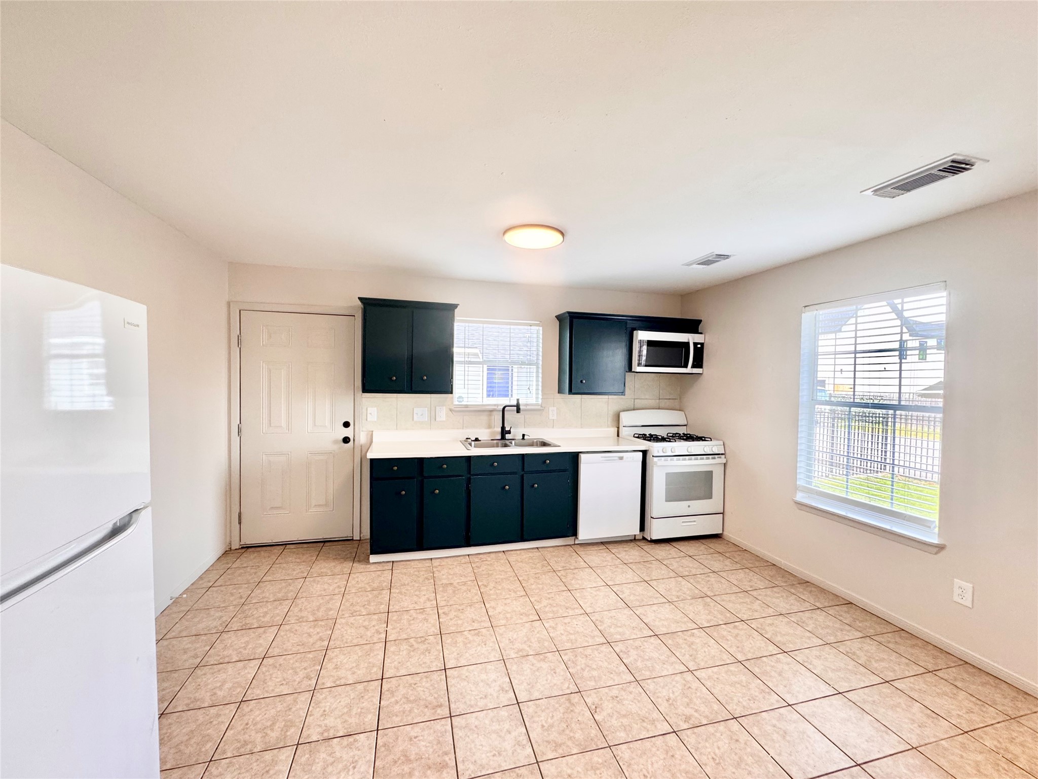 301 Enid Street Houston, TX 77009 - Photo 9 of 34 a large white kitchen with a stove top oven a sink dishwasher and a refrigerator with wooden floor