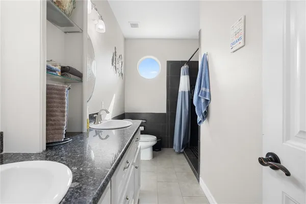 a bathroom with a granite countertop sink a toilet and a mirror