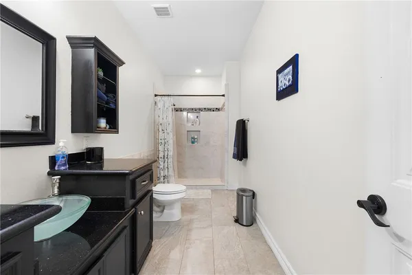a bathroom with a granite countertop sink a toilet and a mirror