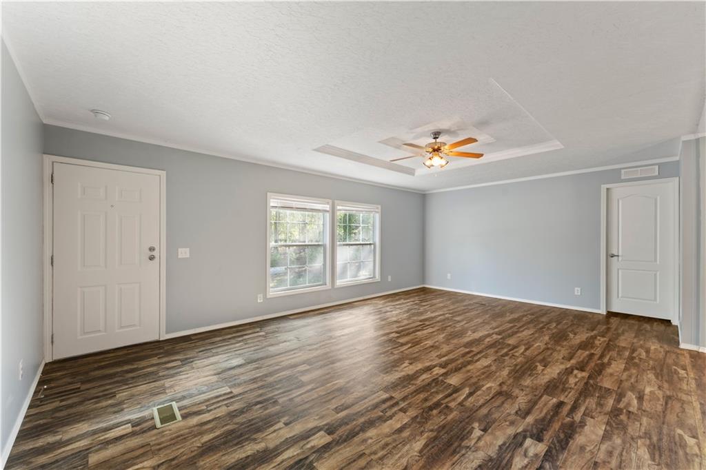 89 Ridge Road Seale, AL 36875 - Photo 6 of 46 Spacious room featuring wood-finish flooring, light blue walls, a white tray ceiling, and a ceiling fan with light fixture