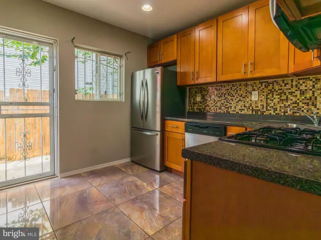 a kitchen with stainless steel appliances granite countertop a refrigerator a stove and a sink