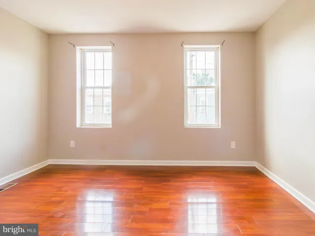 an empty room with wooden floor and windows