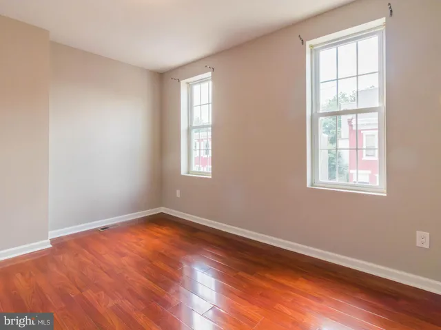 an empty room with wooden floor and windows