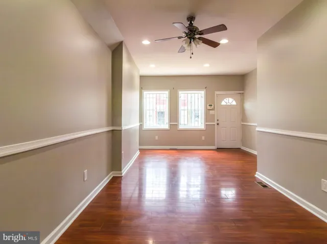 a view of an empty room with window and wooden floor