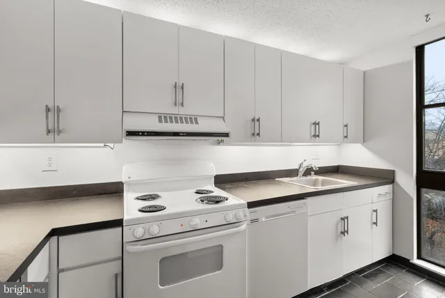 a kitchen with granite countertop white cabinets and white appliances