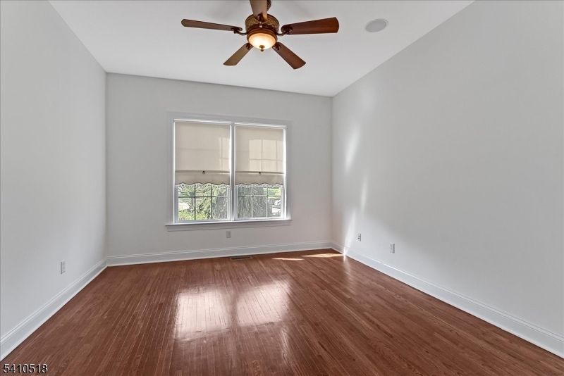 1 Brodziak Road Denville, NJ 07834 - Photo 26 of 42 an empty room with wooden floor ceiling fan and windows