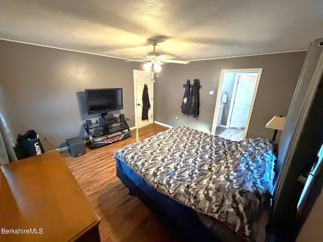 a bedroom with bed and a flat tv screen on dresser
