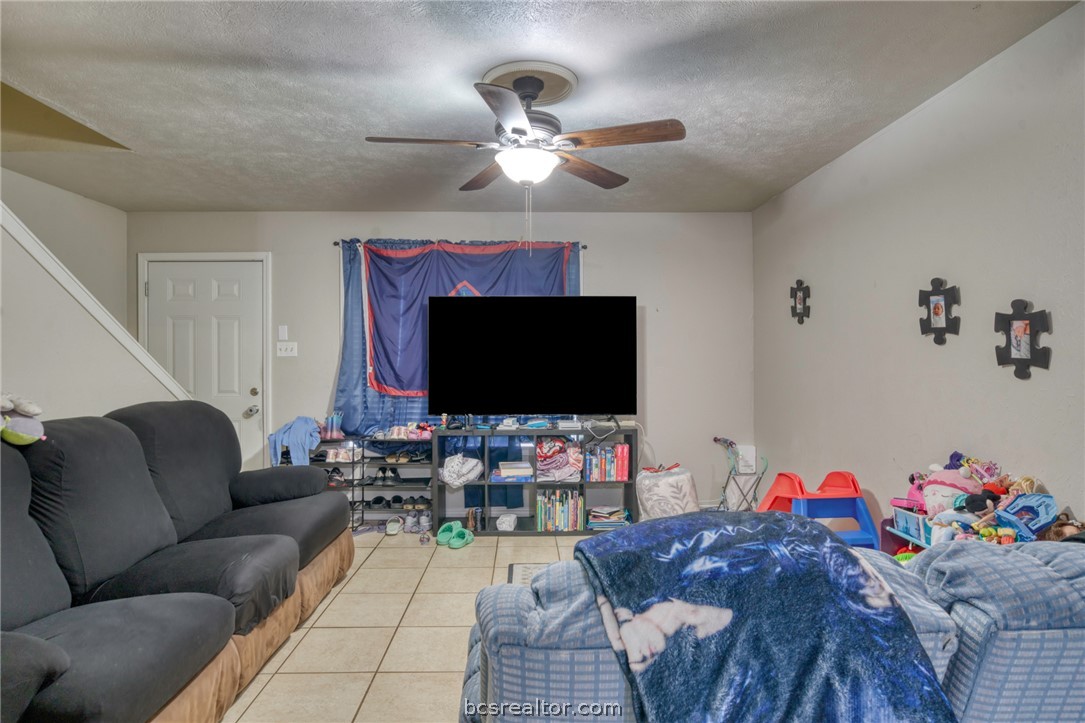 1908 Barak Lane, Unit 14 Bryan, TX 77802 - Photo 4 of 10 Tiled living room featuring ceiling fan and a textured ceiling