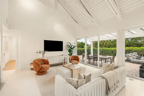 a living room with furniture a flat screen tv and floor to ceiling window