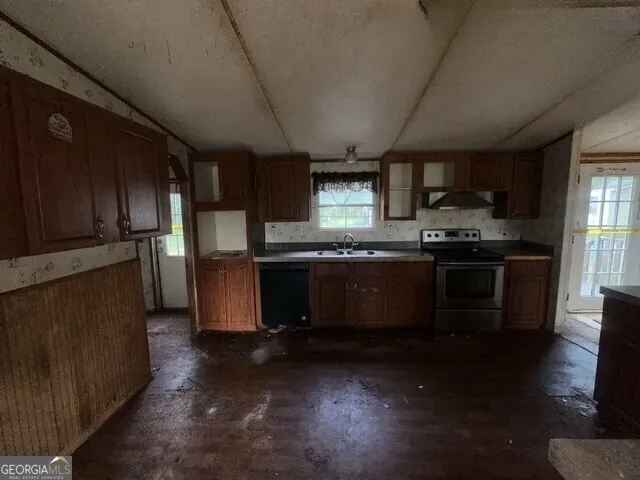 a kitchen with stainless steel appliances granite countertop wooden cabinets a sink a stove a microwave and wooden floors