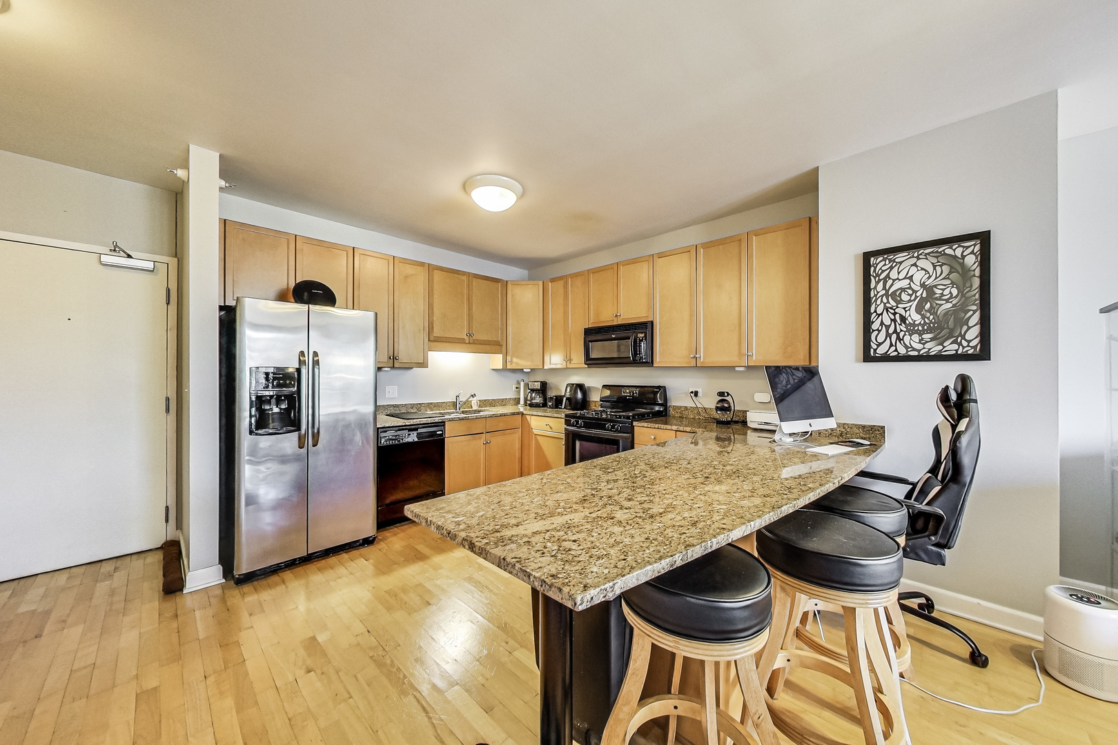 1101 South State Street, Unit 2001 Chicago, IL 60605 - Photo 12 of 24 a kitchen with stainless steel appliances kitchen island granite countertop a refrigerator a stove a sink dishwasher and white cabinets with wooden floor