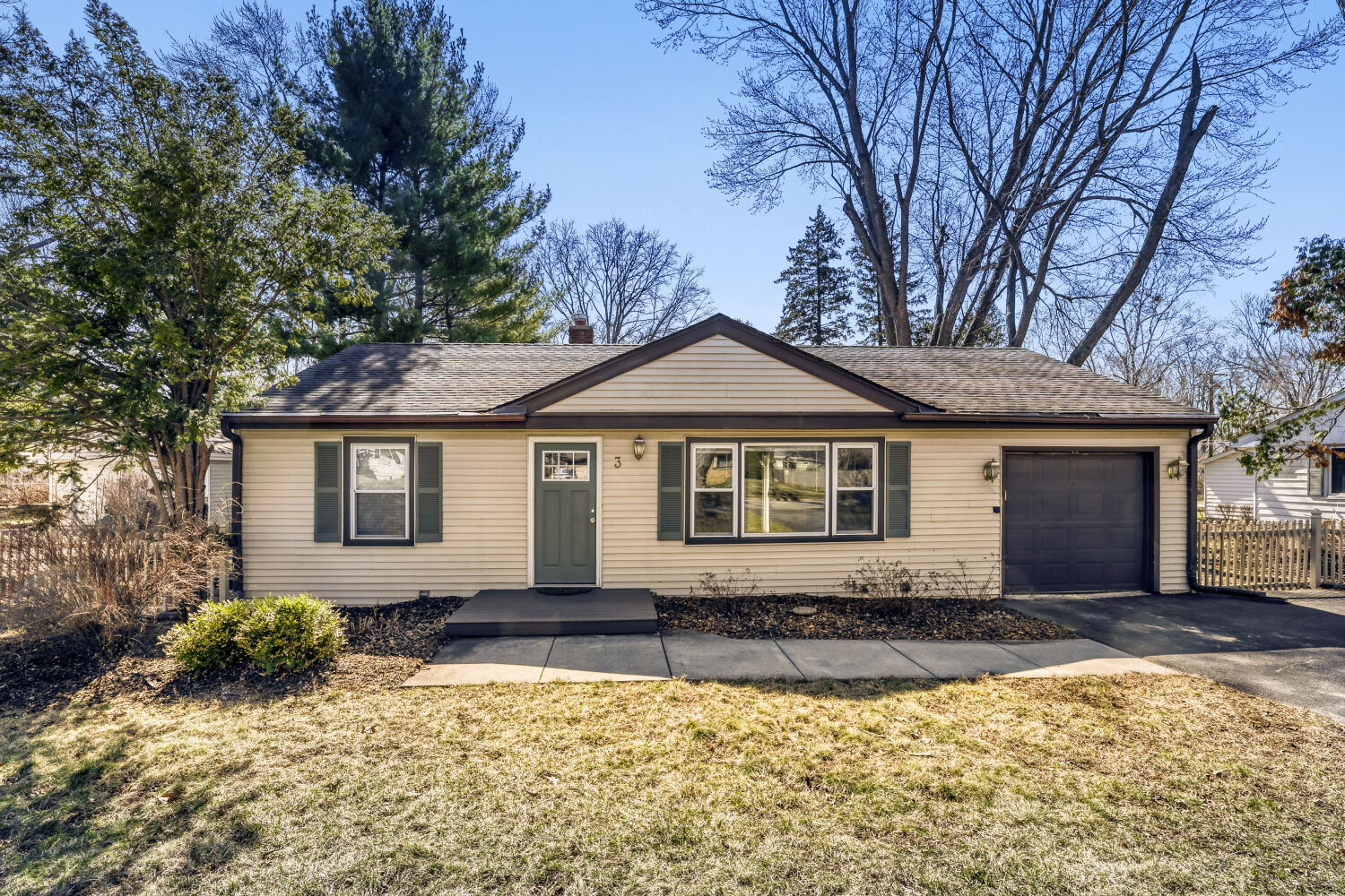 a front view of a house with a yard covered with trees