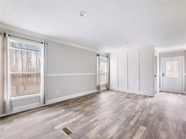 a view of an empty room with wooden floor and windows