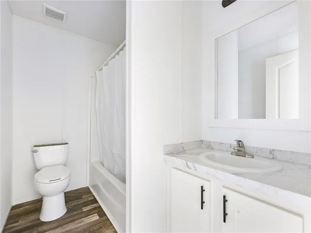 a bathroom with a granite countertop sink toilet and a mirror