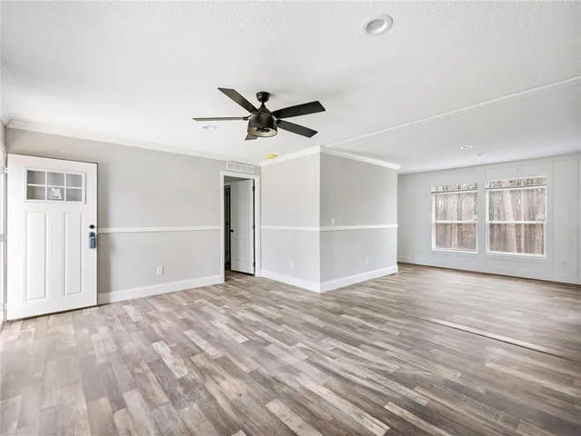 a view of an empty room with a window and wooden floor