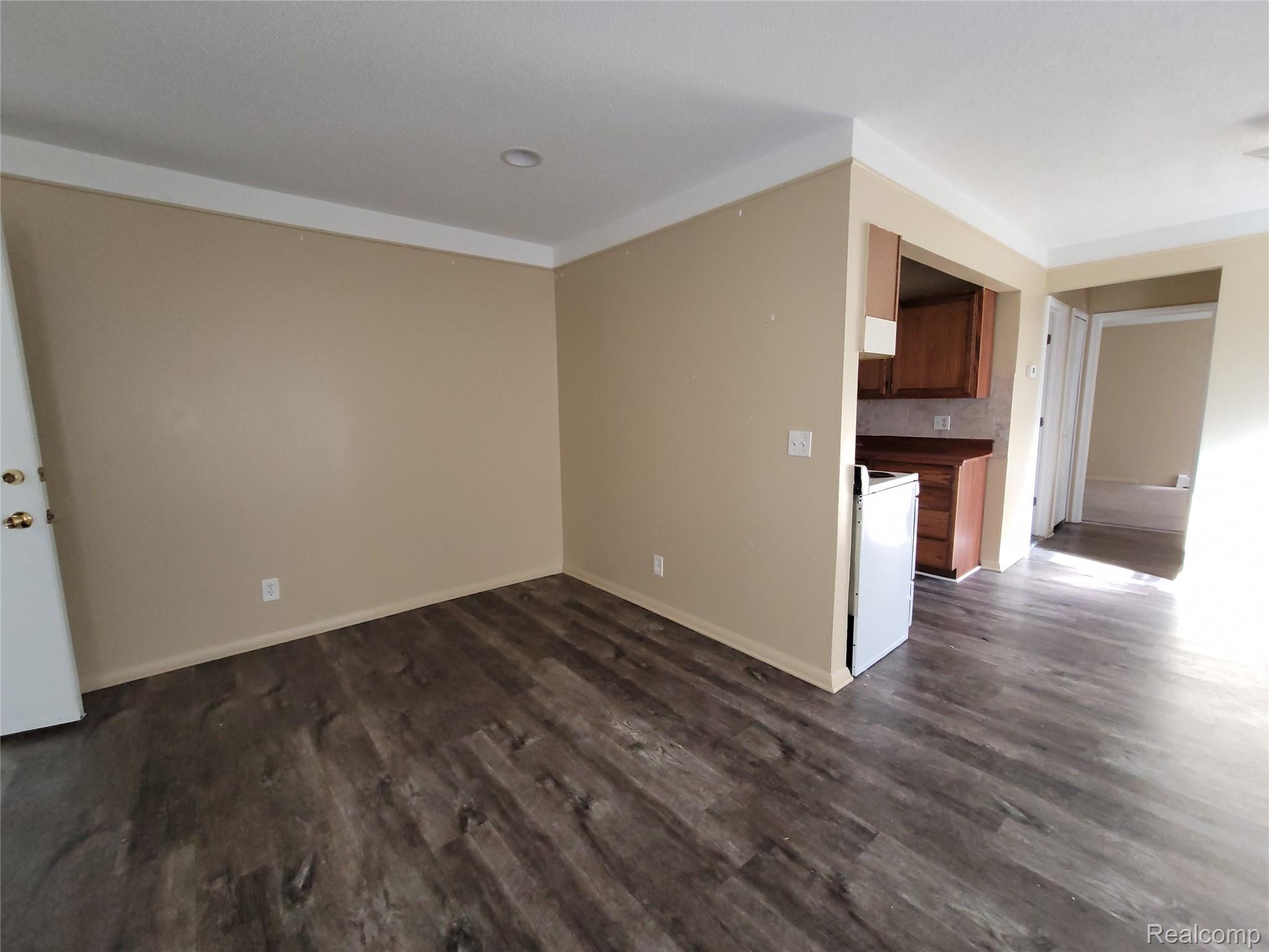 Empty room featuring dark wood-type flooring and baseboards