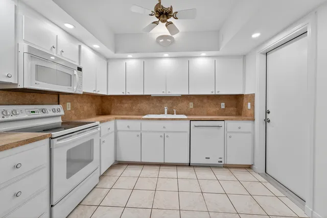 a kitchen with white cabinets granite counter tops and a stove
