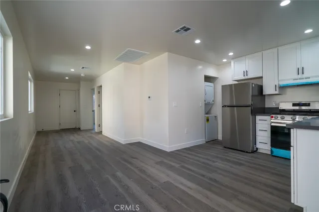an empty room with wooden floor and a refrigerator
