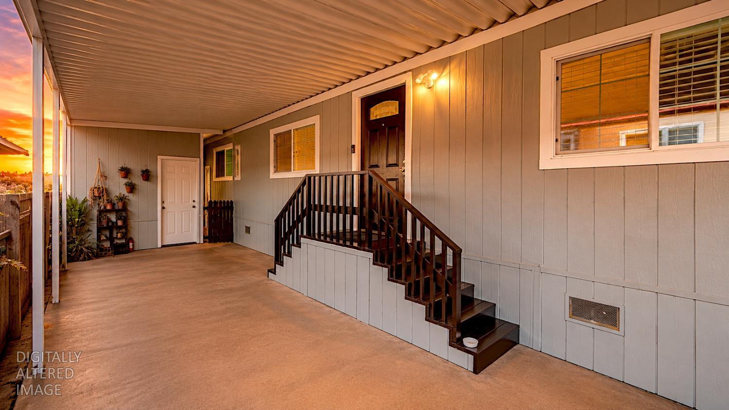 812 West Clover Road, Unit 59 Tracy, CA 95376 - Photo 8 of 51 Covered outdoor patio area featuring a concrete surface, light gray vertical siding, dark wood-finish staircase and railings, and multiple windows