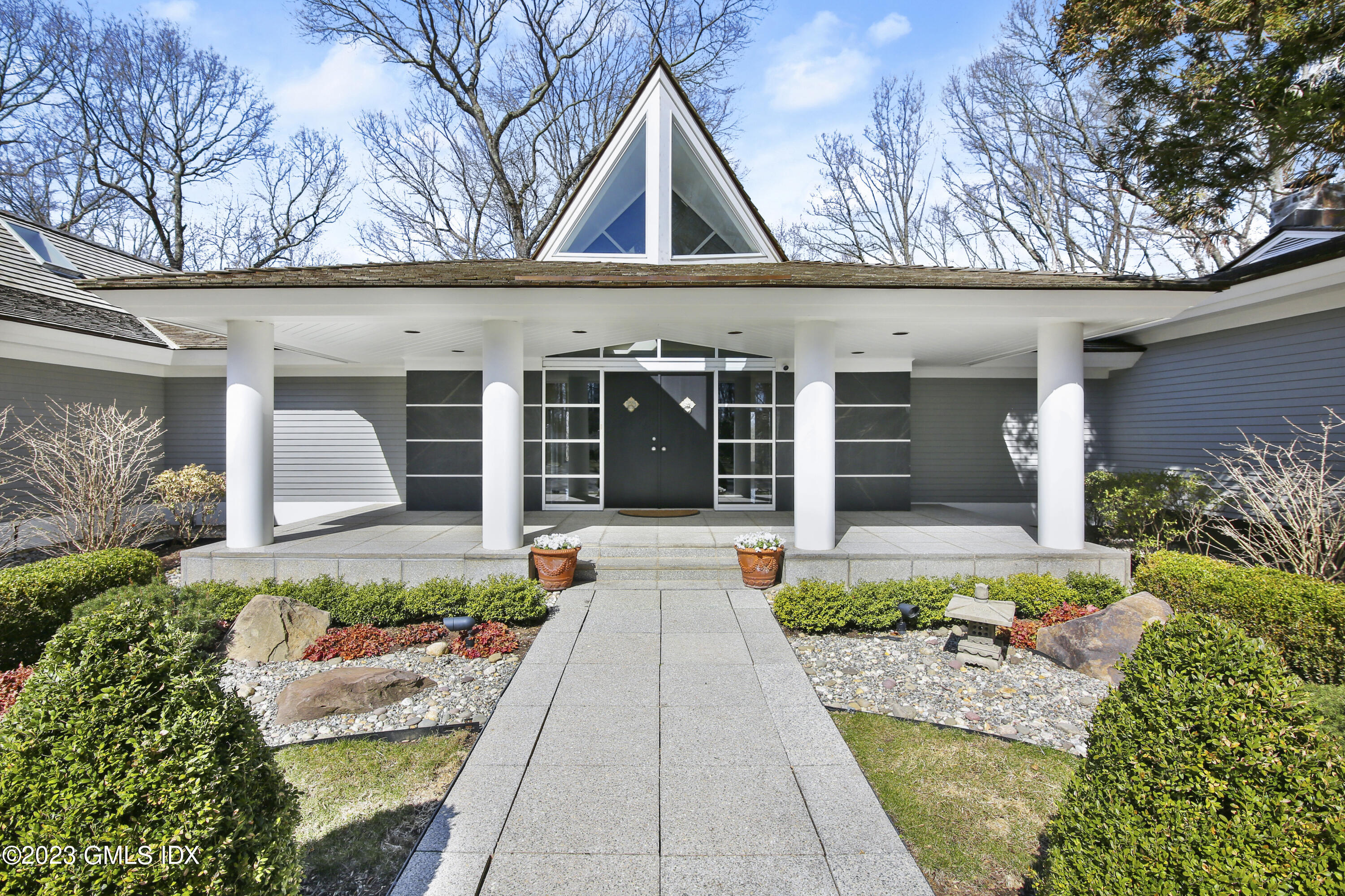 a view of a house with potted plants and a large tree
