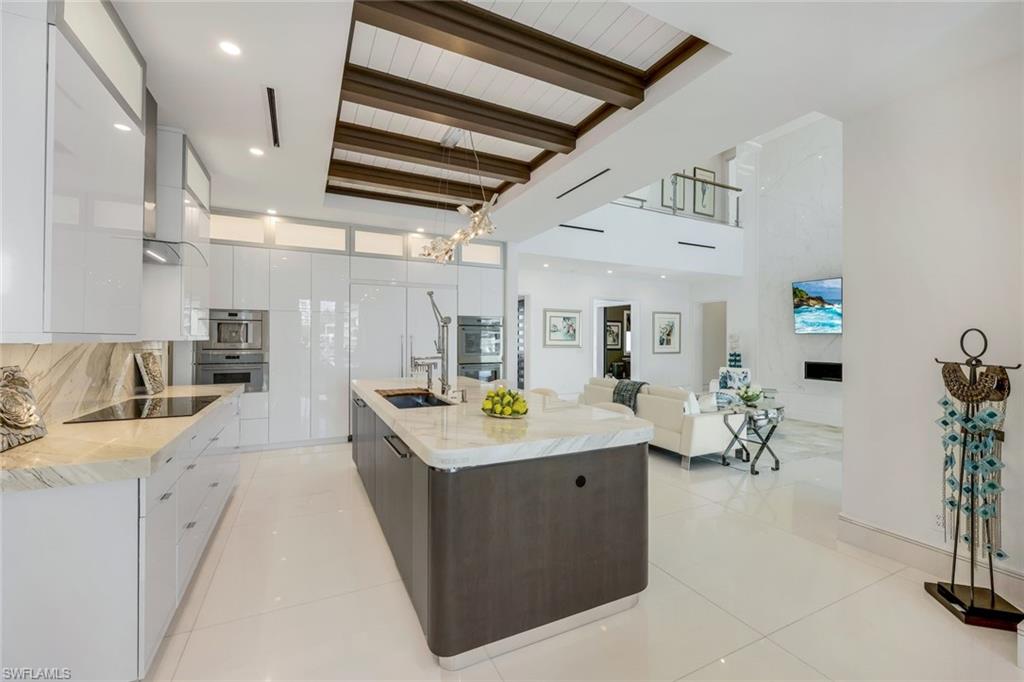 309 Neapolitan Way Naples, FL 34103 - Photo 11 of 33 a kitchen with stainless steel appliances kitchen island granite countertop a sink and cabinets