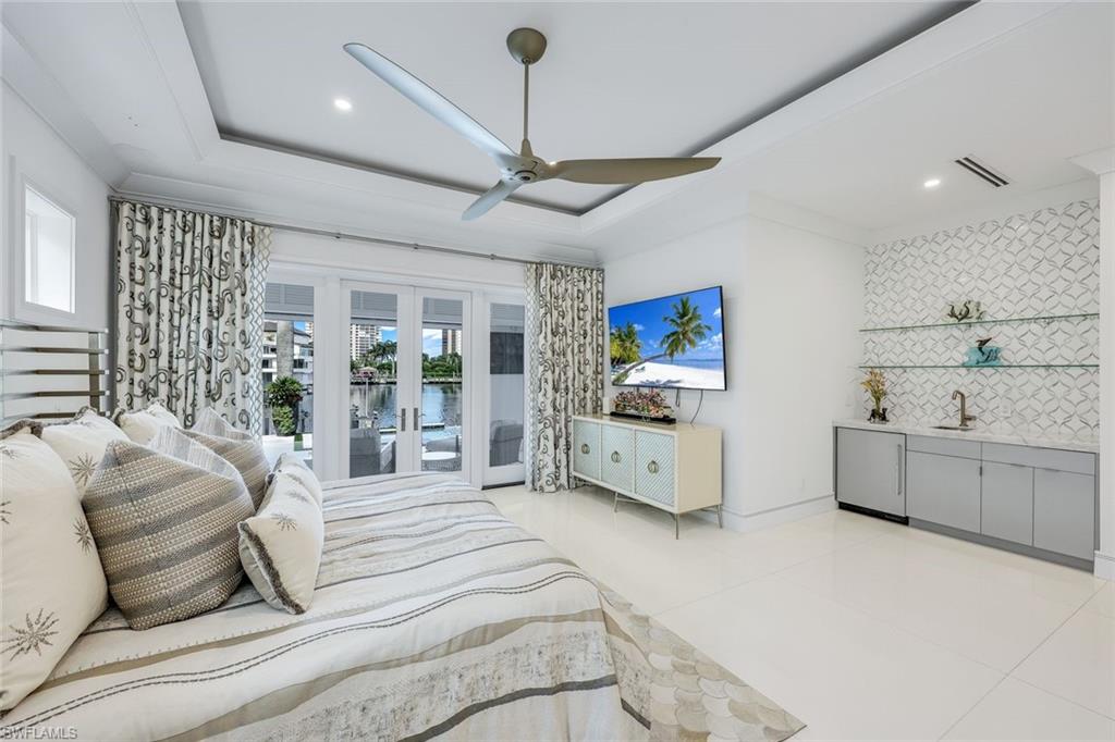 309 Neapolitan Way Naples, FL 34103 - Photo 17 of 33 a spacious bedroom with a large bed and a chandelier