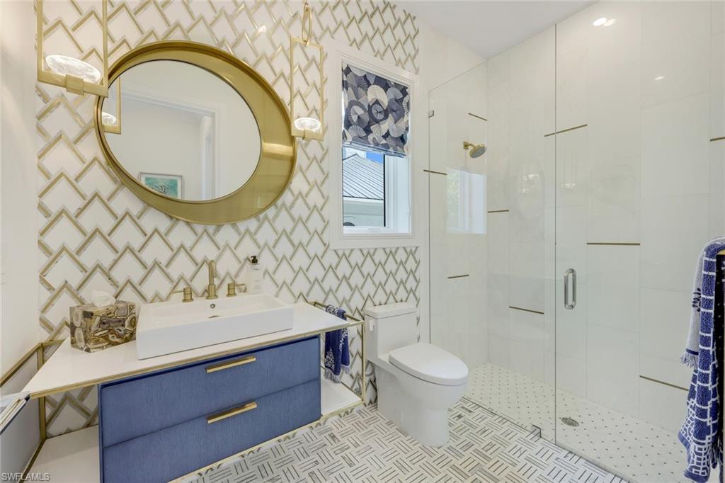 309 Neapolitan Way Naples, FL 34103 - Photo 20 of 33 a bathroom with a sink a mirror a toilet and a shower