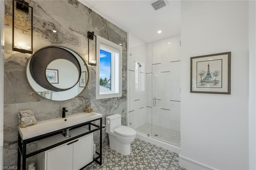 309 Neapolitan Way Naples, FL 34103 - Photo 25 of 33 a bathroom with a toilet a sink a mirror and shower