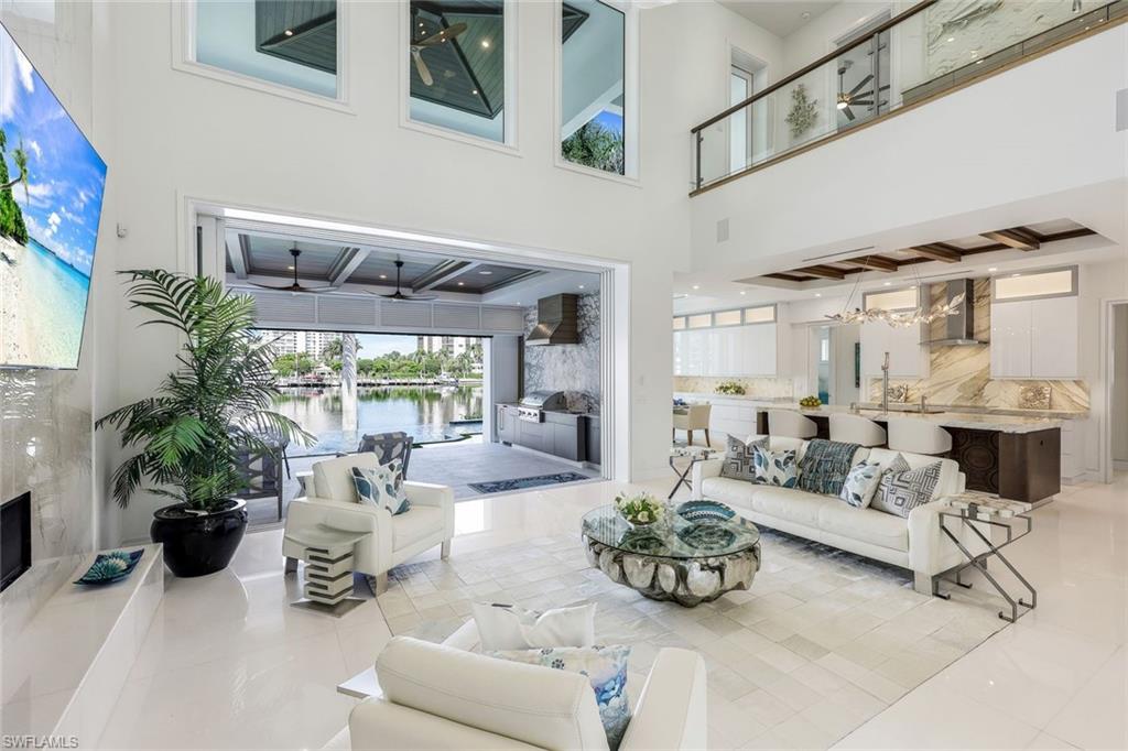 309 Neapolitan Way Naples, FL 34103 - Photo 6 of 33 a living room with furniture and a large window with potted plants